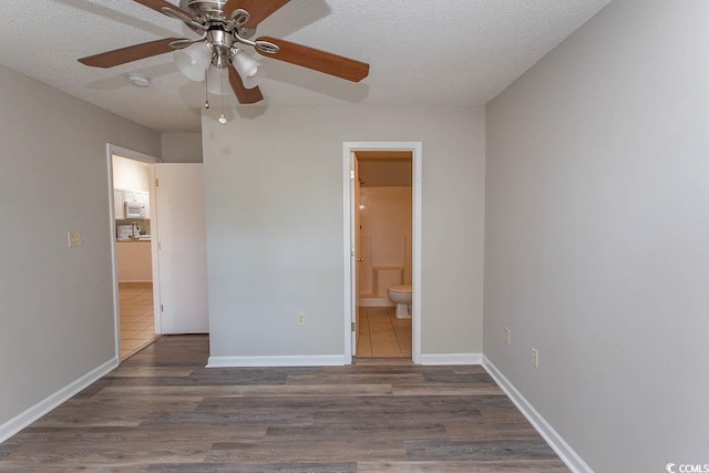 unfurnished bedroom featuring ceiling fan, dark hardwood / wood-style floors, a textured ceiling, and ensuite bath