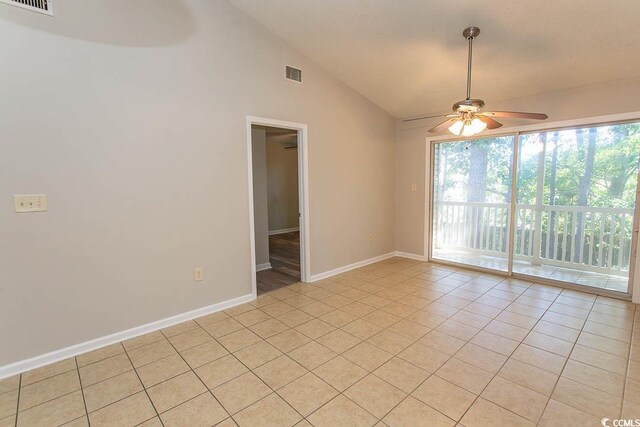 empty room with ceiling fan, light tile patterned floors, and vaulted ceiling