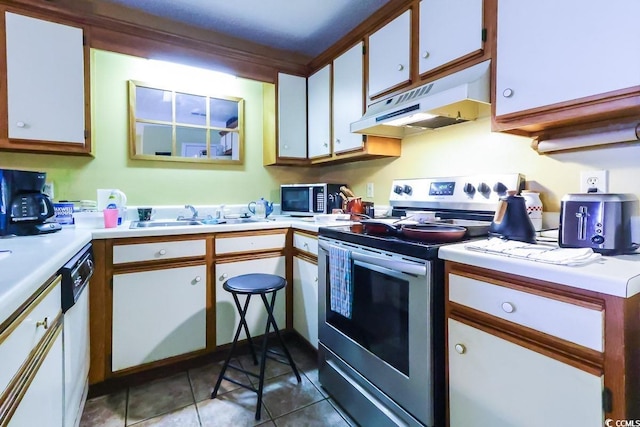 kitchen featuring dark tile patterned flooring, white dishwasher, sink, white cabinets, and stainless steel range with electric stovetop