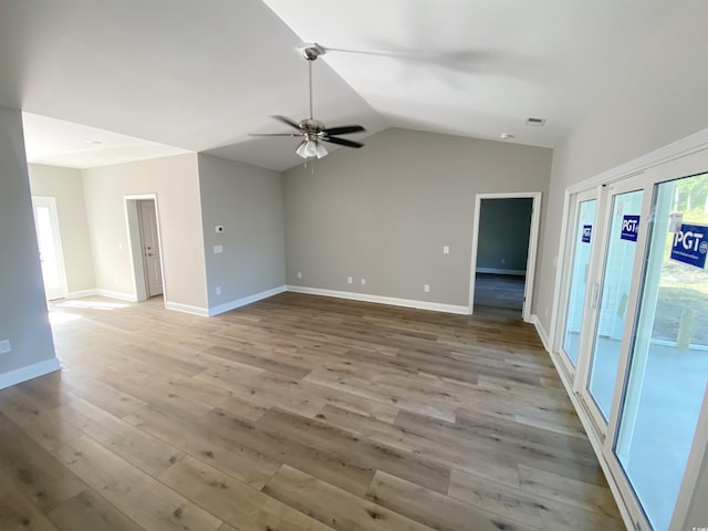 empty room featuring visible vents, wood finished floors, baseboards, lofted ceiling, and ceiling fan