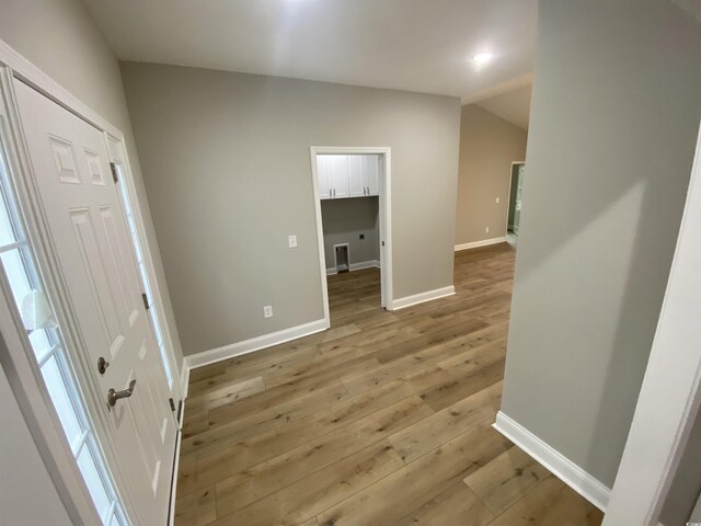 foyer featuring lofted ceiling, light wood-style flooring, visible vents, and baseboards