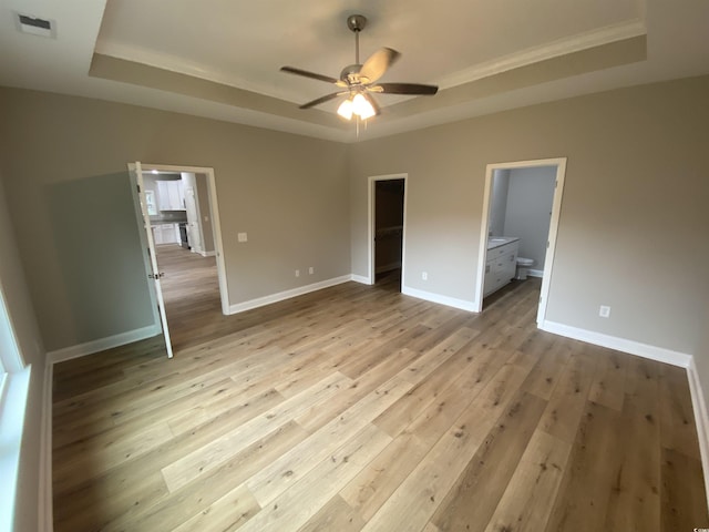 unfurnished bedroom with visible vents, baseboards, light wood-type flooring, and a tray ceiling