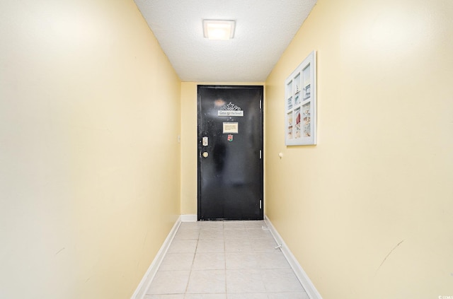 doorway to outside with a textured ceiling and light tile patterned floors