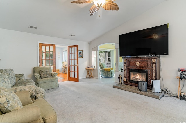 carpeted living room featuring plenty of natural light, lofted ceiling, a fireplace, and french doors