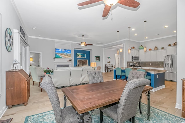 dining space featuring ornamental molding, light wood-type flooring, ceiling fan, and sink