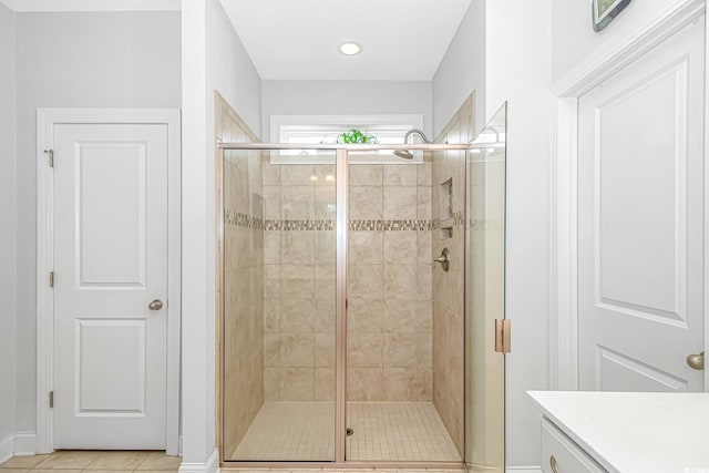 bathroom with tile patterned flooring, a shower with door, and vanity