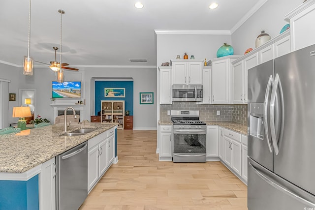 kitchen with appliances with stainless steel finishes, white cabinetry, ceiling fan, light hardwood / wood-style flooring, and sink