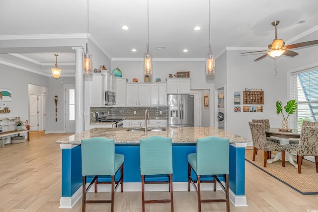 kitchen featuring light stone counters, white cabinets, sink, light hardwood / wood-style flooring, and appliances with stainless steel finishes