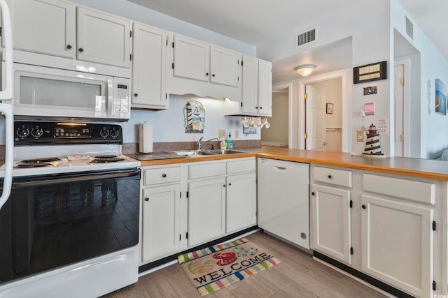 kitchen with light hardwood / wood-style floors, sink, white cabinetry, kitchen peninsula, and white appliances