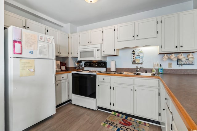 kitchen with white appliances, sink, dark wood-type flooring, and white cabinets