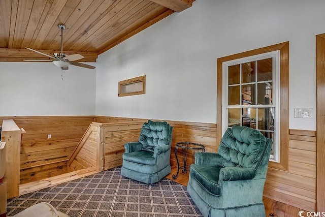 living area with wooden ceiling, lofted ceiling, wood walls, and ceiling fan