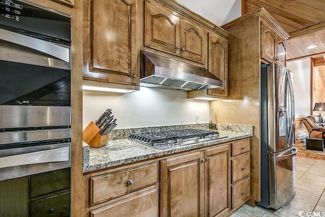 kitchen with light stone counters, appliances with stainless steel finishes, and light tile patterned floors