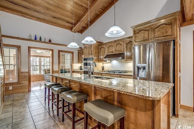 kitchen featuring vaulted ceiling with beams, light tile patterned flooring, wood ceiling, an island with sink, and sink