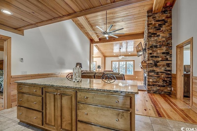 kitchen with wood ceiling, light wood-type flooring, vaulted ceiling with beams, light stone countertops, and ceiling fan