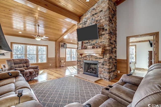 living room featuring ceiling fan, a stone fireplace, wood ceiling, and plenty of natural light