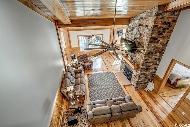 living room with wooden ceiling, a stone fireplace, ceiling fan, and hardwood / wood-style flooring