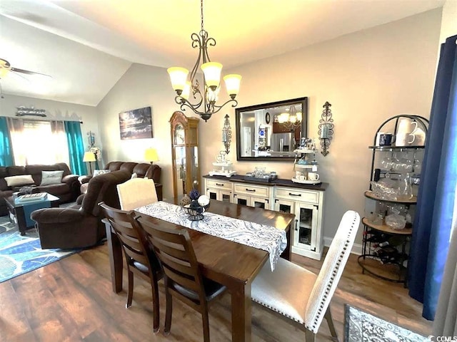 dining space with lofted ceiling, dark wood-style flooring, and ceiling fan with notable chandelier