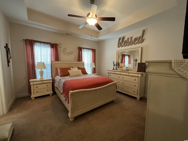 bedroom featuring carpet floors, a tray ceiling, and a ceiling fan