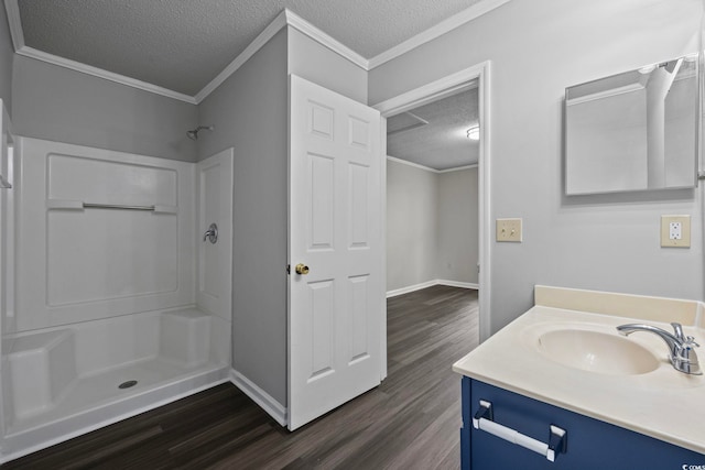 bathroom with a textured ceiling, walk in shower, vanity, crown molding, and hardwood / wood-style flooring