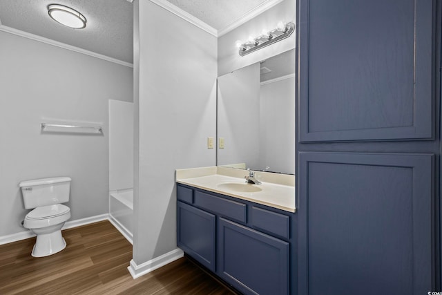 bathroom with toilet, hardwood / wood-style floors, crown molding, vanity, and a textured ceiling