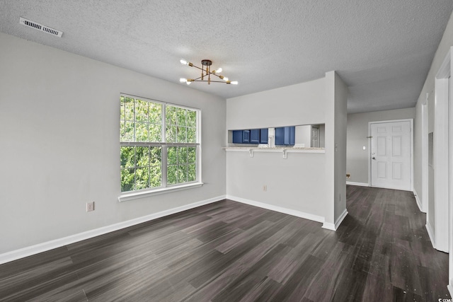 empty room featuring a chandelier, a textured ceiling, and dark hardwood / wood-style flooring