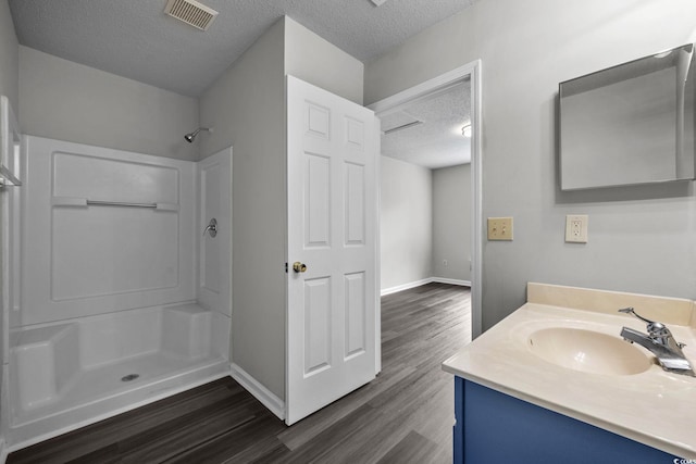 bathroom featuring vanity, a shower, a textured ceiling, and hardwood / wood-style floors