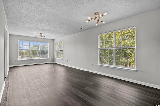 spare room featuring a notable chandelier, a textured ceiling, and dark wood-type flooring