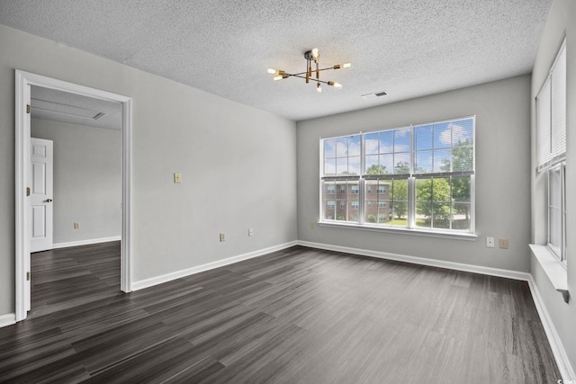 spare room featuring dark wood-type flooring, a textured ceiling, and an inviting chandelier