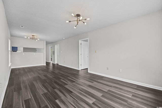 unfurnished living room with a notable chandelier, a textured ceiling, and dark wood-type flooring