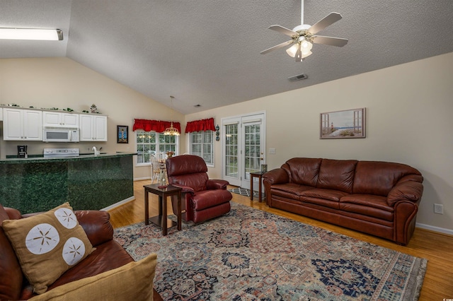 living room with ceiling fan, a textured ceiling, lofted ceiling, and light hardwood / wood-style flooring