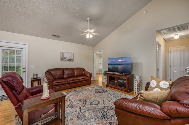 living room featuring ceiling fan, hardwood / wood-style flooring, a textured ceiling, and high vaulted ceiling