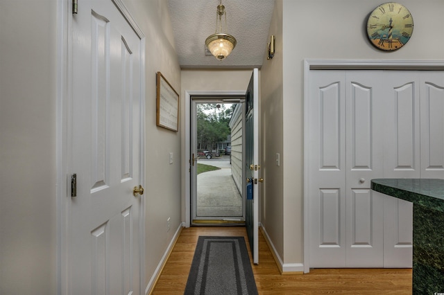 doorway featuring light wood-type flooring and a textured ceiling