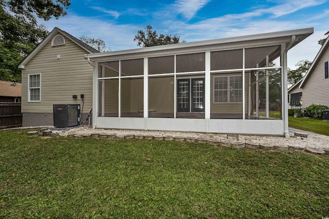 rear view of house featuring a sunroom, a yard, and central AC