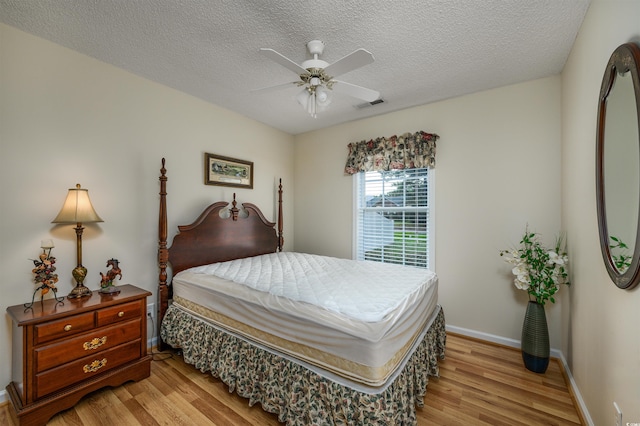 bedroom with light wood-type flooring, a textured ceiling, and ceiling fan