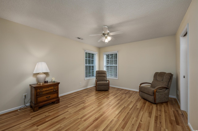 sitting room with ceiling fan, a textured ceiling, and light hardwood / wood-style floors