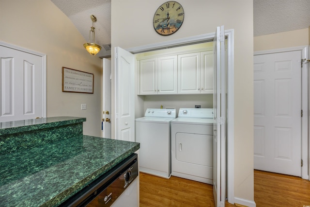 laundry area featuring washer and clothes dryer, cabinets, light hardwood / wood-style floors, and a textured ceiling