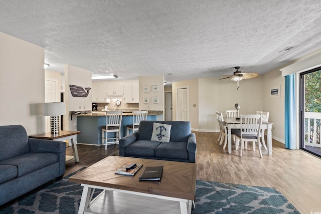 living room with ceiling fan, dark wood-type flooring, and a textured ceiling