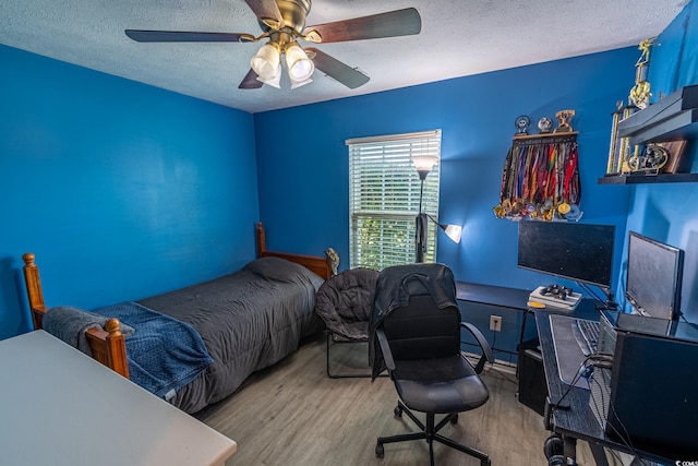 bedroom with ceiling fan, a textured ceiling, and light hardwood / wood-style flooring