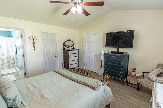 bedroom featuring wood-type flooring, connected bathroom, vaulted ceiling, and ceiling fan