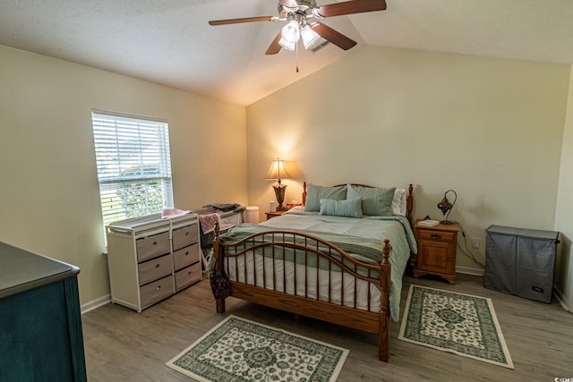 bedroom featuring light hardwood / wood-style flooring, vaulted ceiling, and ceiling fan