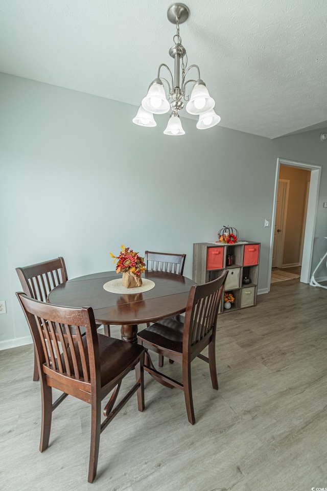 dining area with an inviting chandelier, a textured ceiling, and hardwood / wood-style flooring