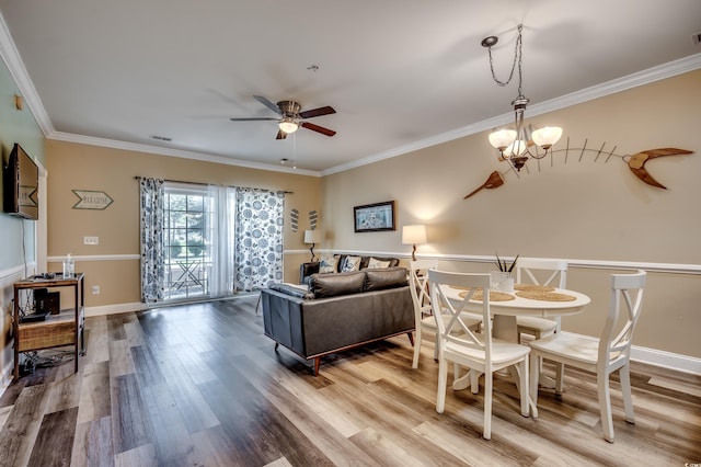 interior space with ceiling fan with notable chandelier, ornamental molding, and wood-type flooring