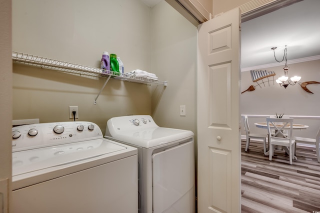 laundry area with hardwood / wood-style floors, ornamental molding, an inviting chandelier, and independent washer and dryer