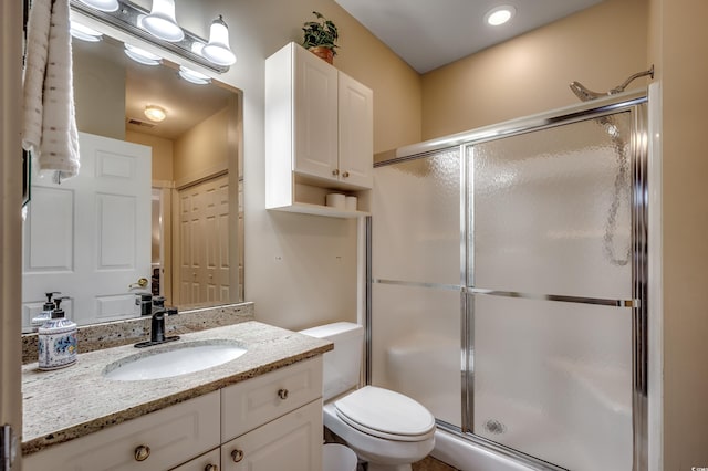 bathroom with a shower with door, vanity, and toilet