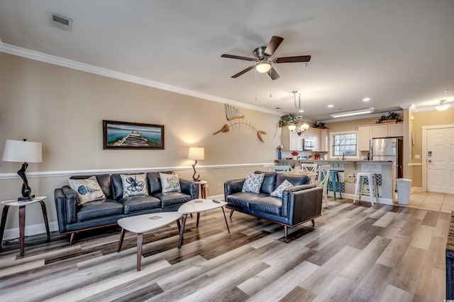 living room featuring light wood-type flooring, ceiling fan, sink, and crown molding