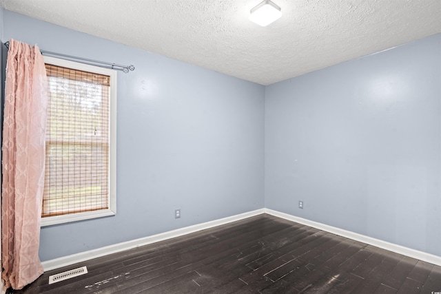 empty room with a textured ceiling and dark hardwood / wood-style flooring