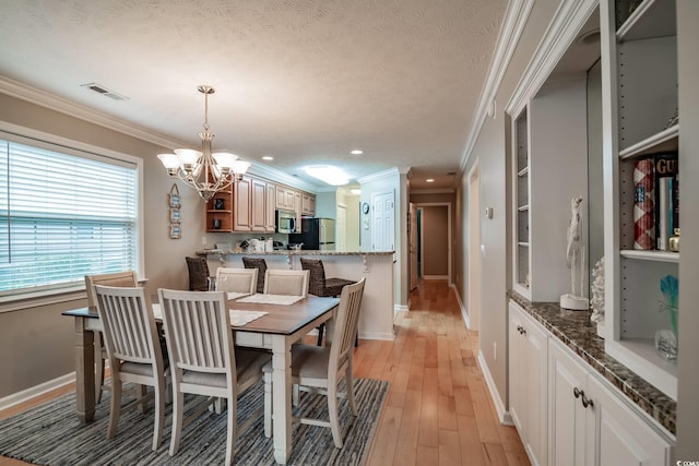 dining space featuring baseboards, a notable chandelier, ornamental molding, and visible vents