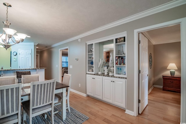 dining room featuring crown molding, baseboards, light wood finished floors, and a chandelier