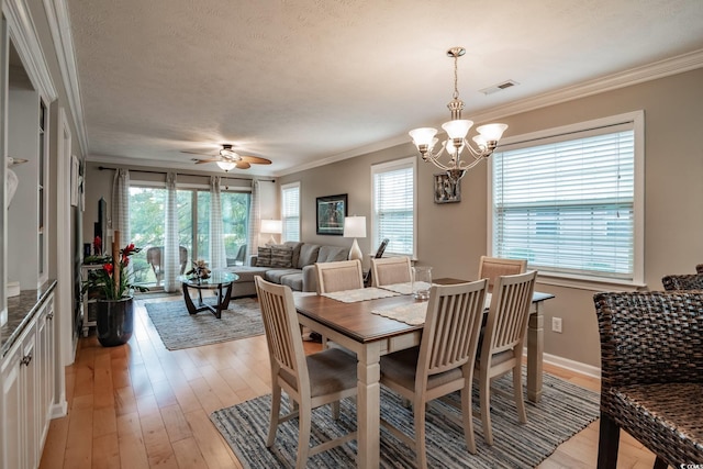 dining room with light wood-style flooring, a textured ceiling, a healthy amount of sunlight, and ornamental molding