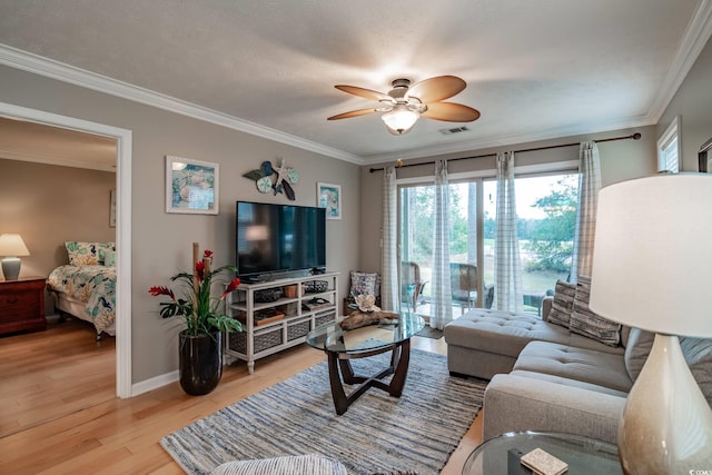 living room with visible vents, baseboards, a ceiling fan, light wood-style floors, and crown molding